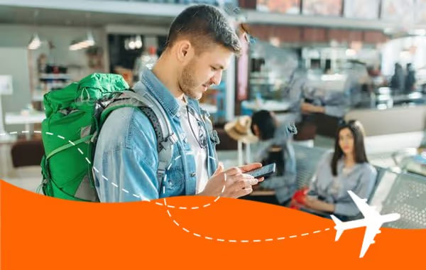Backpacker checking his phone in an airport terminal while travelling with a SimYak eSIM