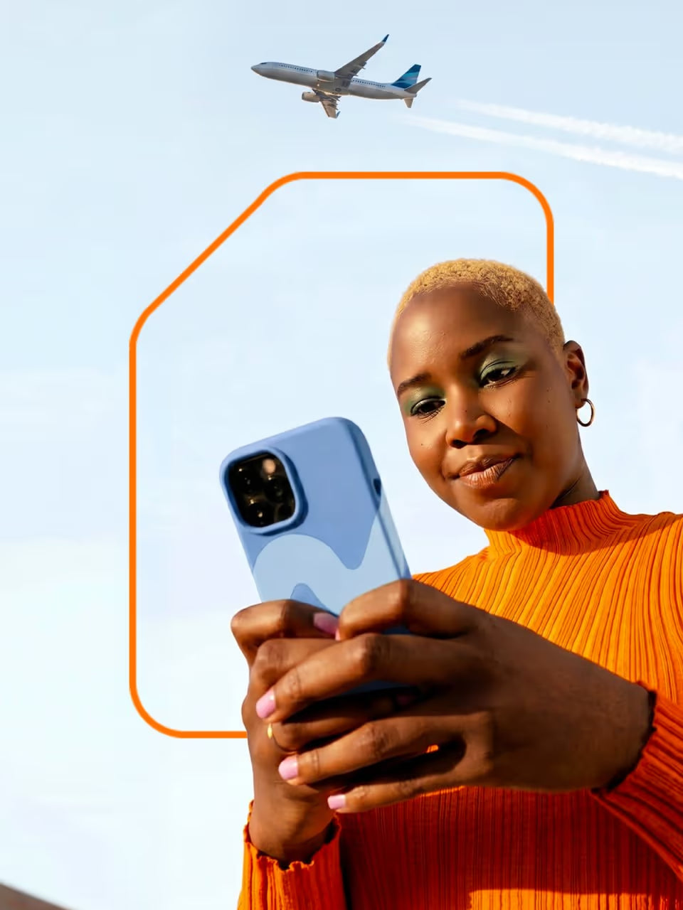 Viajera tomándose una selfie con su teléfono bajo un cielo azul despejado mientras un avión sobrevuela