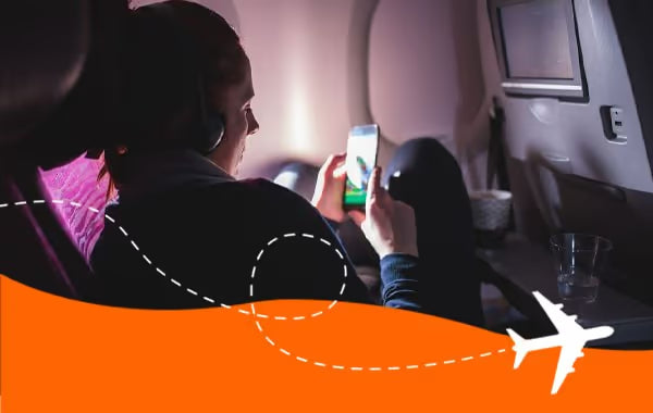 Airline passenger using her phone with headphones during a flight